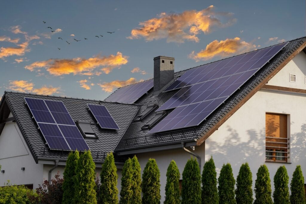 Large modern house with solar panels on a pitched roof. 