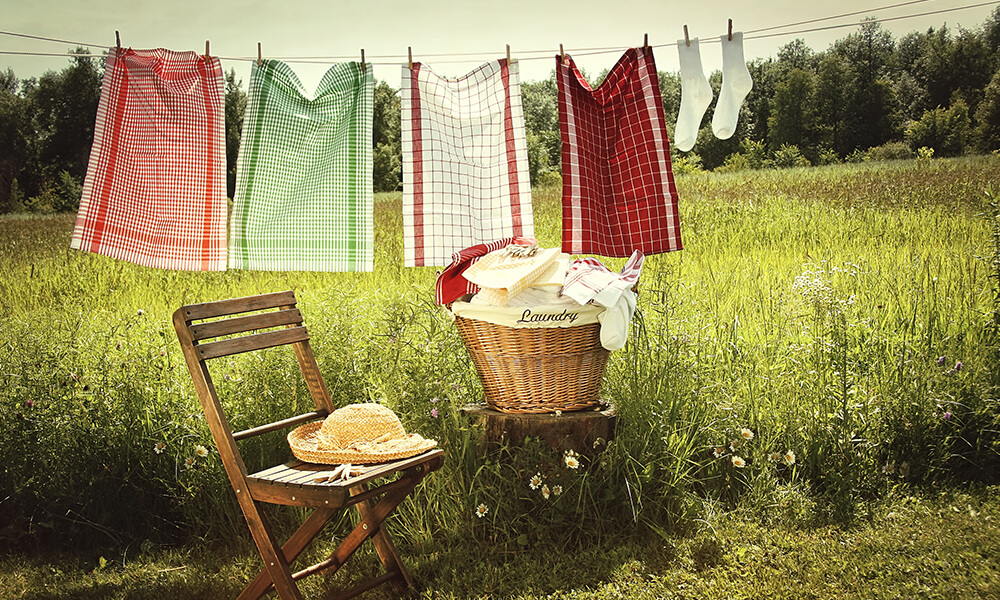 a cloths line outside with hanging towels and a chair and a small pile of laundry