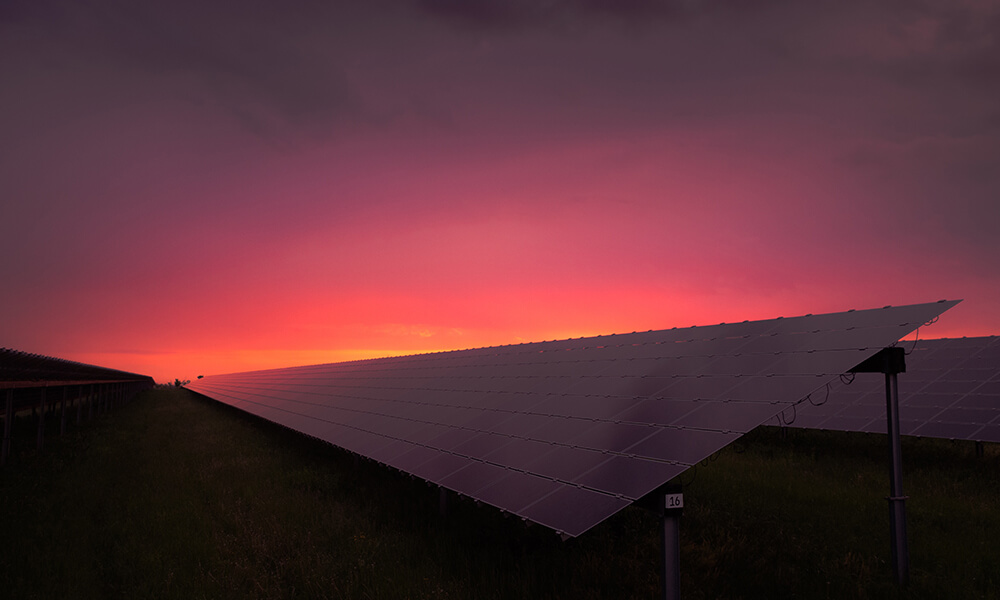 a dramatic photo of a solar panel at sunset with a pink sky