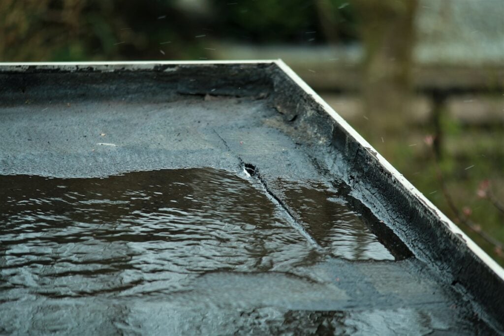 Water pooling on a black flat roof after hail