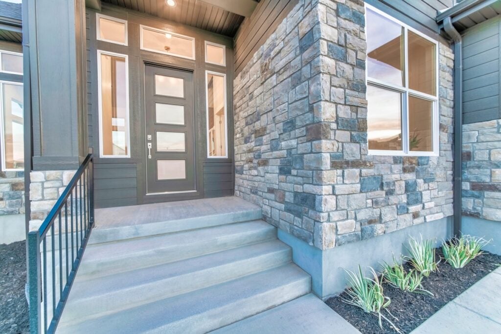 Home with stone brick wall and gray front door with frosted glass panels.