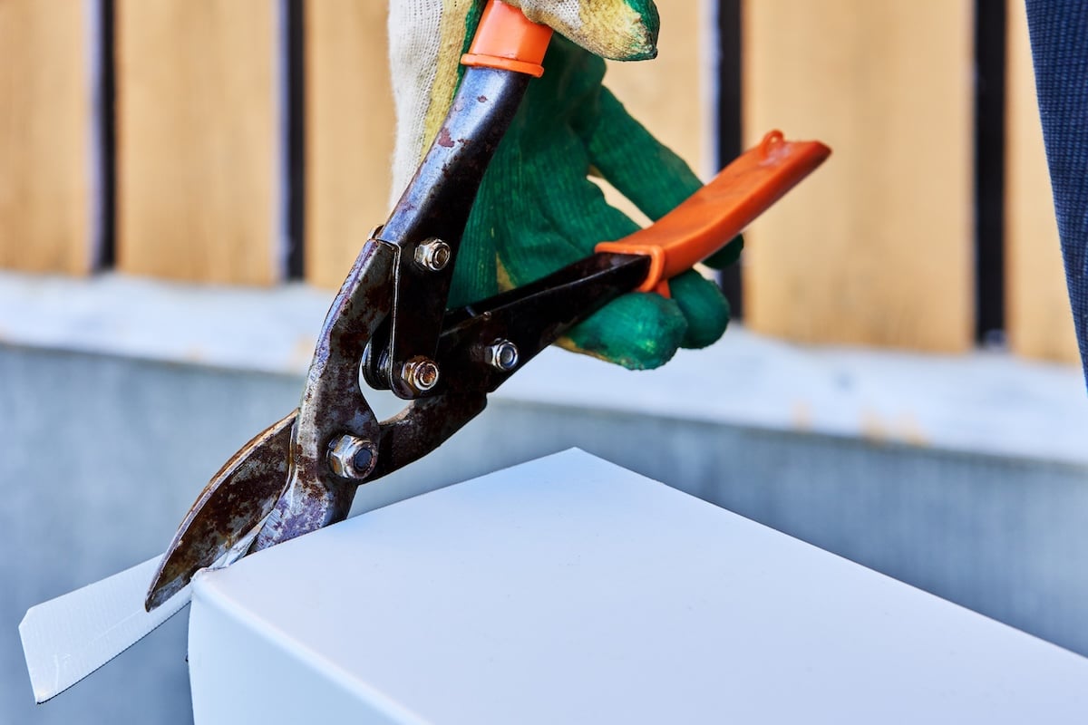 Sheet metal snips for right handed cutting, roofer cuts edge of window slope made of galvanized steel.