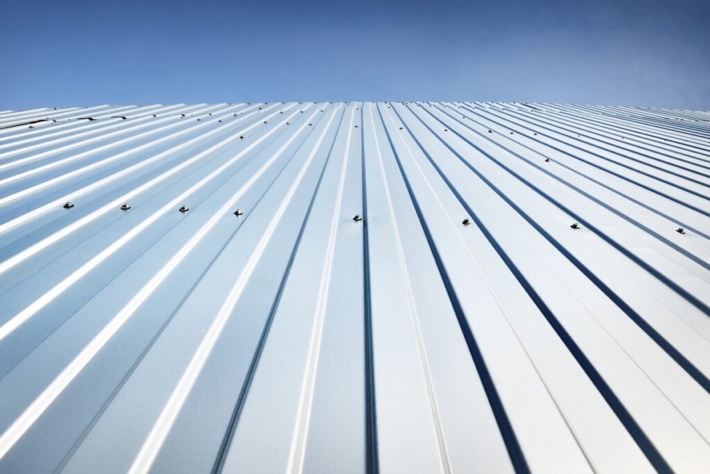 Low angle view of the silvery warehouse wall. Metal siding, texture, close-up