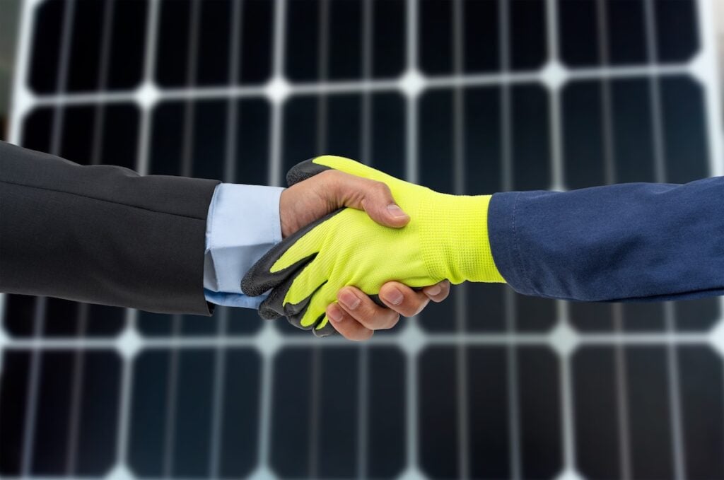 handshake in front of solar panels