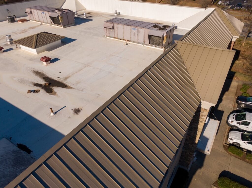Sunny Day Time Drone Images of Standing Seam Metal Roof on a Commercial Building Also Featuring TPO.