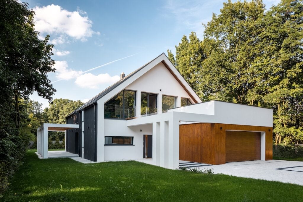 Exterior view of modern, white house with garage decorated with wood