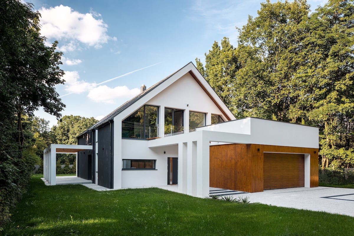 Exterior view of modern, white house with garage decorated with wood