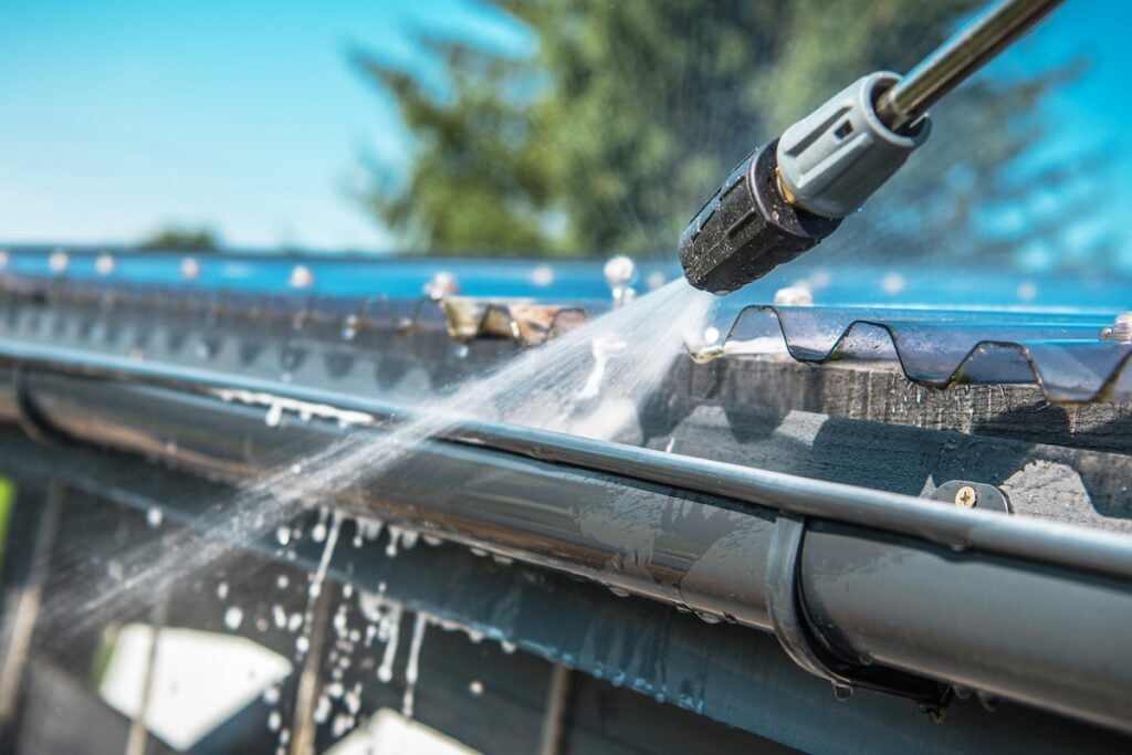 Spring Rain Gutters Cleaning Using Pressure Washer. 