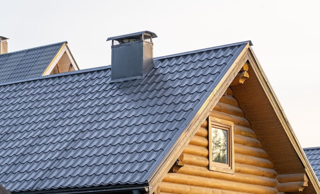 A log cabin features a sleek metal shingle roof and chimney