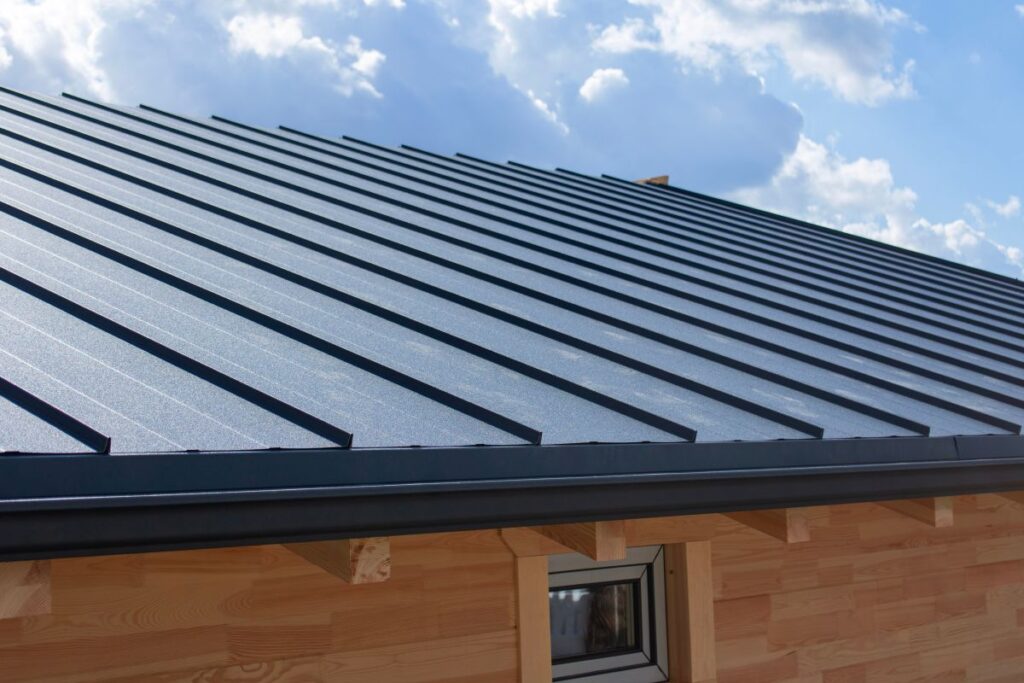 Dark gray standing seam metal roof and black gutter system on a building with natural wooden walls