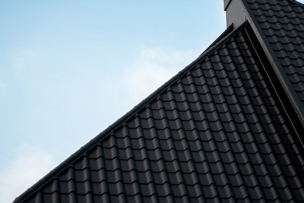 close-up of a black metal tile roof against a blue sky