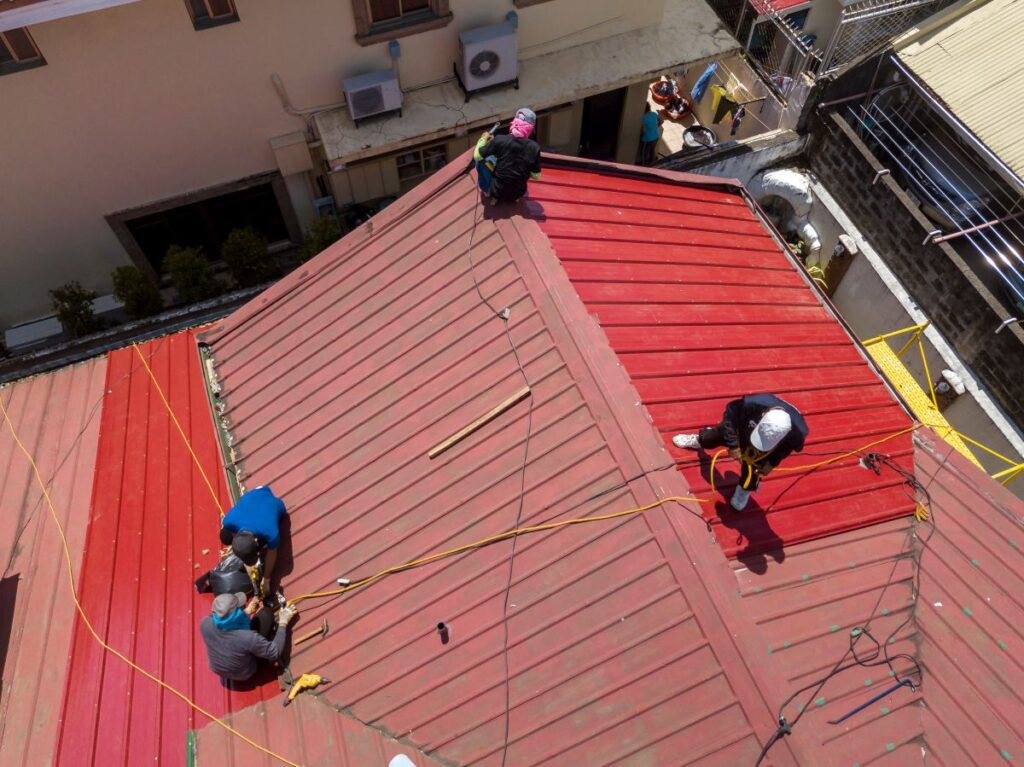 do you need to close your business during a roof replacement workers replacing red metallic panels