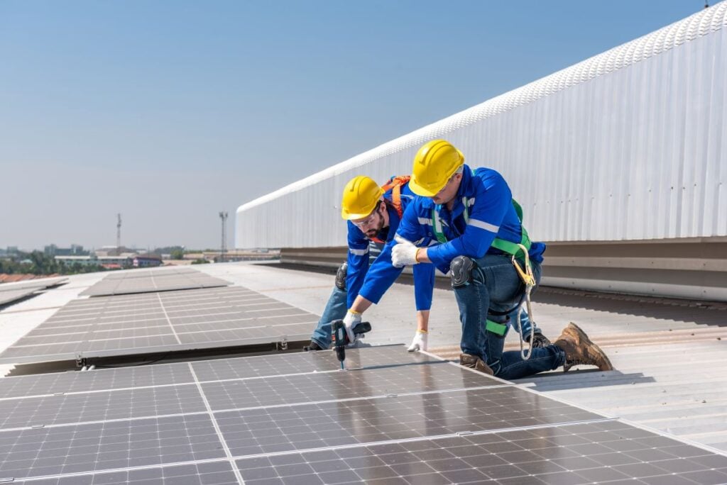 commercial solar installation worker drilling pannels