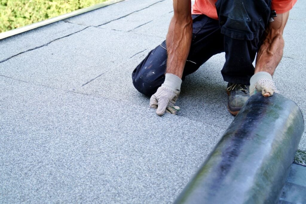 flat roof replacement worker installing new asphalt cover