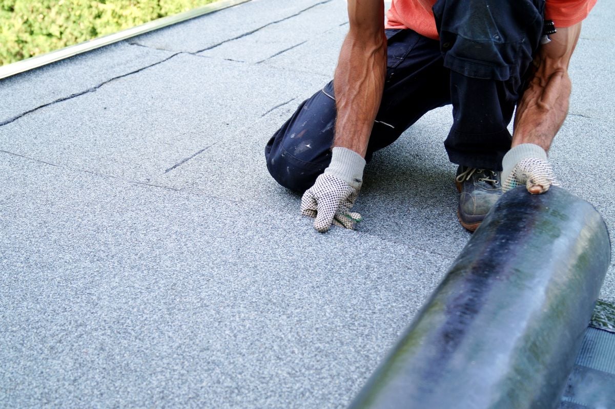 flat roof replacement worker installing new asphalt cover