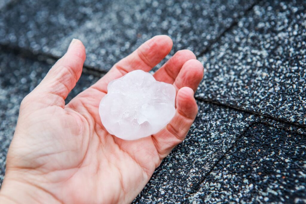 hail damage roof inspection hand holding piece of ice