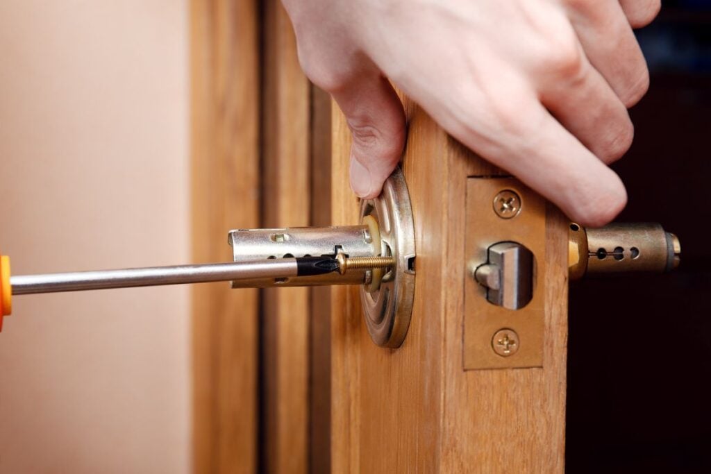 Door installation, worker Installs door knob, woodworker hands close up