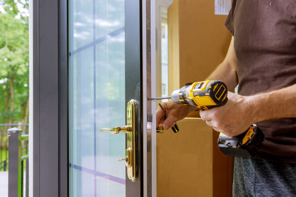 entry door replacement cost worker holding screwdriver to adjust door