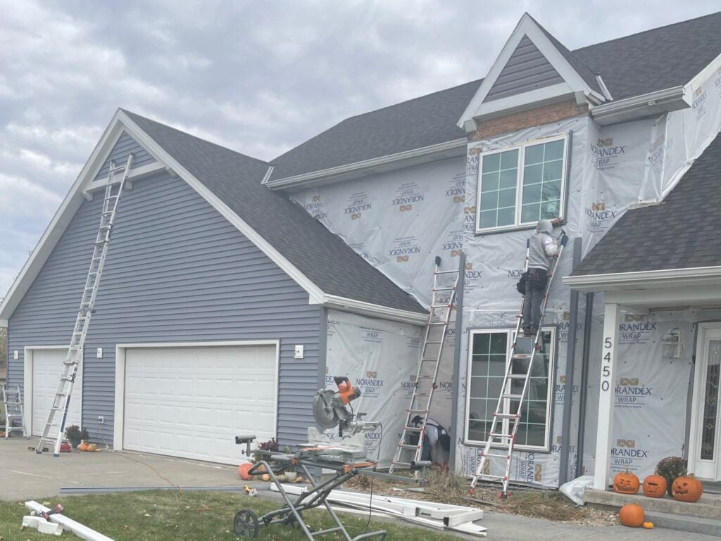 fiber cement siding vs vinyl grey shingles roof workers repairing siding